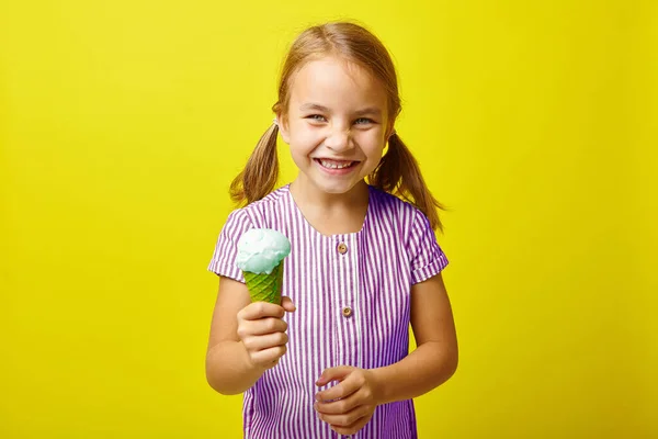 Garotinha rindo com sorvete, retrato em fundo amarelo isolado . — Fotografia de Stock