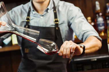 Şarap garsonu karıştırma kabından bardağa şarap dolduruyor. Erkek garson.