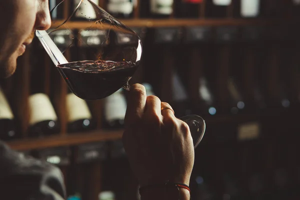 Detailní záběr mladý sommelier vůně červené víno na vinném sklepě pozadí. — Stock fotografie