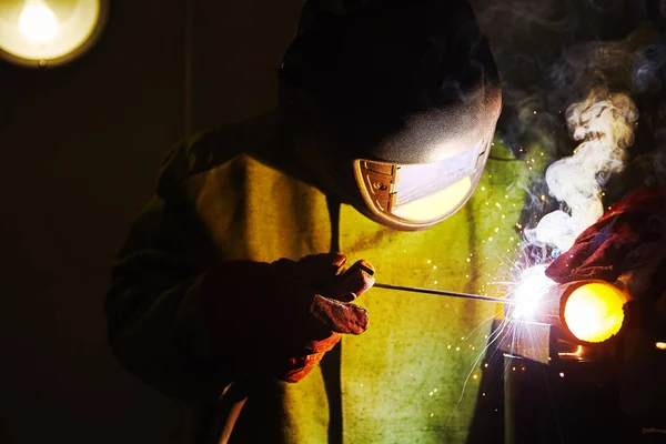 Работник защитной маски сваривает металл на промышленных предприятиях . — стоковое фото