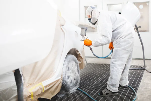 Pintor profesional de coches masculinos está pintando en el garaje por aerógrafo. El hombre trabaja con pistola. — Foto de Stock