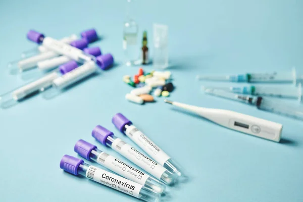 Tubos médicos com amostras de esfregaço para análise de coronavírus sobre fundo azul. — Fotografia de Stock