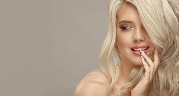 Luxe close-up portret van blanke lachende vrouw met perfecte krullend blond haar en make-up, kijkt weg op beige achtergrond — Stockfoto