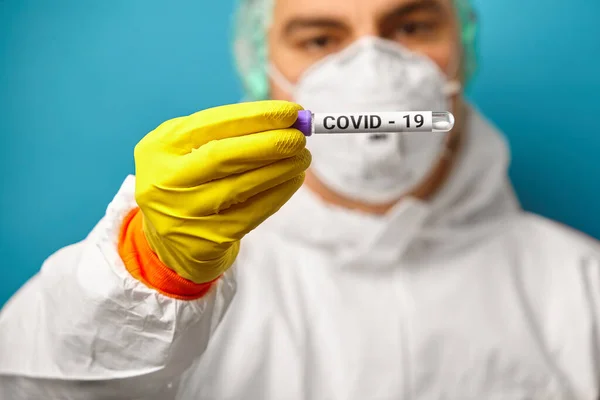 Imagem do médico que usa máscara respiratória e macacão de proteção segurando um resultado de teste expresso para o Coronavirus. Amostra de Covid-19. — Fotografia de Stock