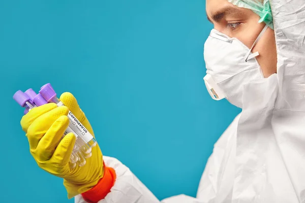 マスクおよび保護カバーを着用した研究室技術者は、コロナウイルスの検査用医療チューブを保持しています. — ストック写真