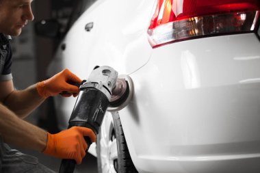 Otomobil tamir atölyesinde orbital cilalayıcısı olan beyaz bir araba, yakın plan. Araç ayrıntıları.