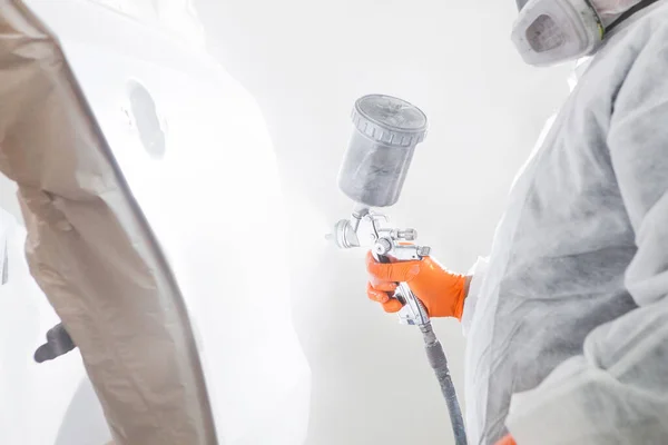 Painting the car in the paint room, spray gun with white paint.