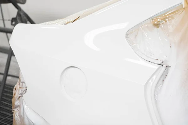 Festés a fehér autó karosszéria a spray standon a karosszéria javító műhely, elemek borított védő papír. — Stock Fotó
