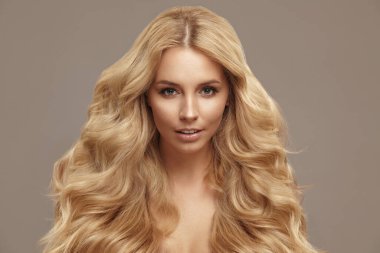 Güzellik stüdyosu portresi, kıvırcık saçlı çekici beyaz kadın. Bej kaplamalı temiz ciltli yetişkin bir kız..