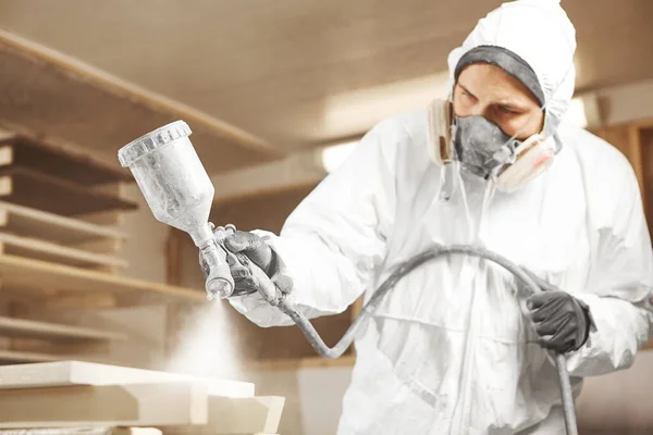 Homem em máscara respiradora pintando pranchas de madeira na oficina. — Fotografia de Stock