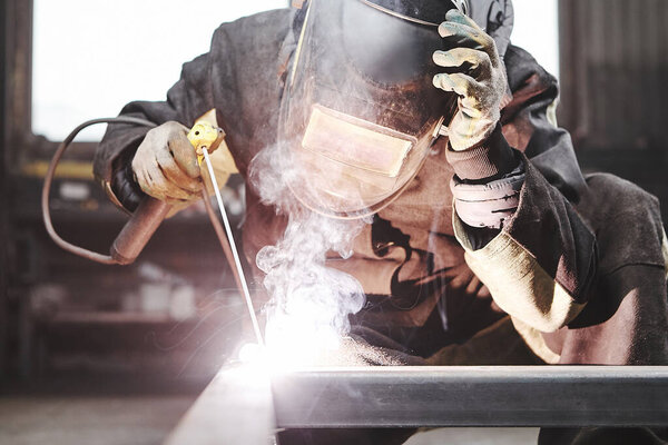 Man in protective mask welding metal construction.