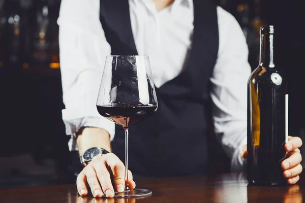 Csapos a bárban egy pohár vörösborral és üveggel, közelkép.. — Stock Fotó