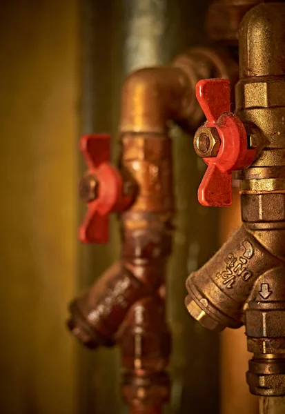 Old water pipes, hot and cold water, with red valves. Vertical orientation. Close up.