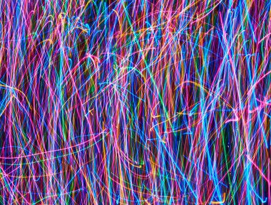 Siyah arkaplandaki soyut renkli ışık çizgileri. Mavi, yeşil, turuncu, pembe çizgiler ve kıvrımlar.