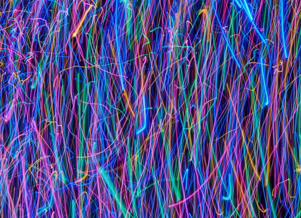 Siyah arkaplandaki soyut renkli ışık çizgileri. Mavi, yeşil, turuncu, pembe çizgiler ve kıvrımlar.