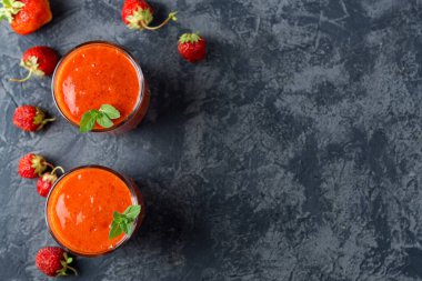 Masada iki bardakta çilek kırmızısı ev yapımı smoothie.