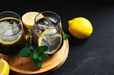 Siyah bir masa üzerinde kömür ve nane ile ferahlatıcı yaz detoks limonatası.