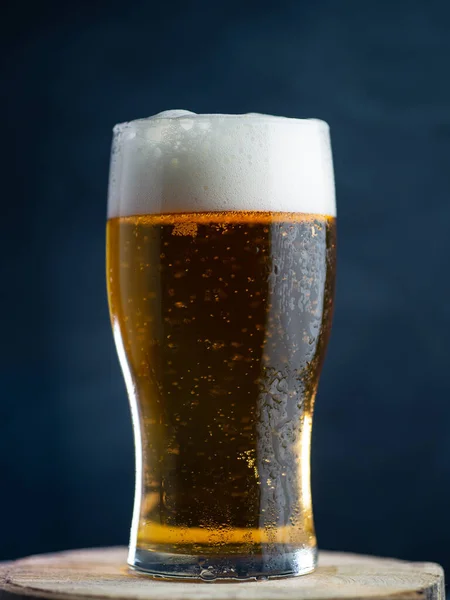 Koyu bir arka planda bir bardak hafif bira.