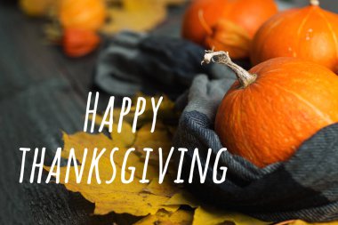 Turuncu balkabaklarının arka planında Şükran Günü yazısı ve ahşap arka planda sonbahar yaprakları.