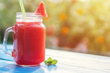 Mavi bir masada cam bardakta karpuz limonatası.