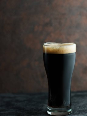 Kahverengi arka planda bir bardakta siyah bira taşıyıcısı.