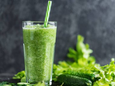 Cam bardakta yeşil meyve püresi ve içinde malzemeler olan bir pipet.