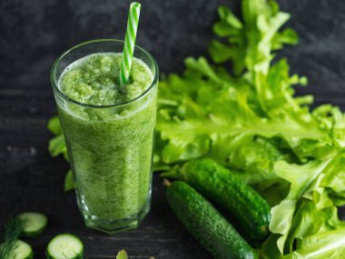 Cam bardakta yeşil meyve püresi ve içinde malzemeler olan bir pipet.