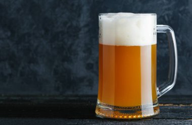 Bardaki beton duvarın arka planında filtrelenmemiş cam bardak bira ve fotokopi alanı.