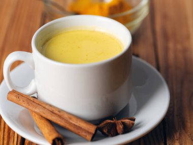 Tahta masanın üzerinde zerdeçal içeren altın süt