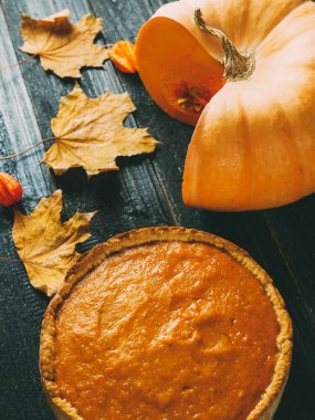 Sonbahar kuru yapraklı, siyah ahşap bir masada balkabağı turtası. Şükran Günü 'nün neşeli şarkısı.