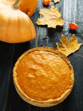 Sonbahar kuru yapraklı, siyah ahşap bir masada balkabağı turtası. Şükran Günü 'nün neşeli şarkısı.