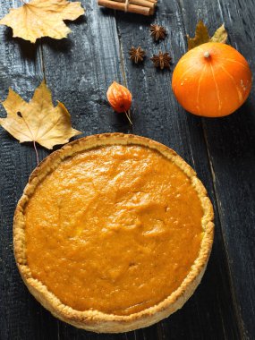 Sonbahar kuru yapraklı, siyah ahşap bir masada balkabağı turtası. Şükran Günü 'nün neşeli şarkısı.