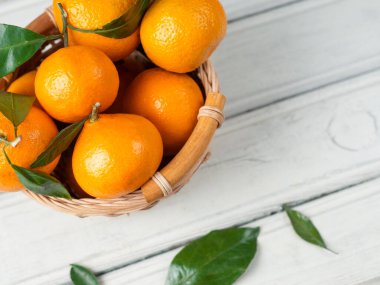 Ahşap bir masanın üzerindeki yapraklarla nefis, olgun mandalinalar.