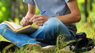 Parkta kitap ya da ders kitabı olan bir öğrenci