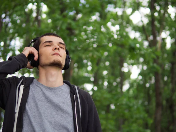 Beautiful man in headphones listening to music outdoor.