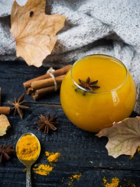 Tahta arka planda süt ve baharatlı zerdeçal çayı