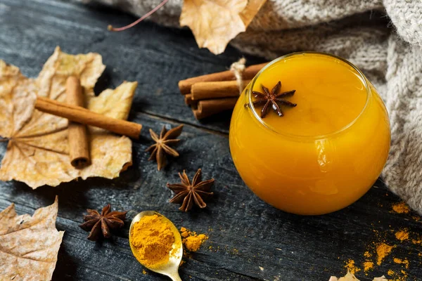 turmeric tea with milk and spices on wooden background