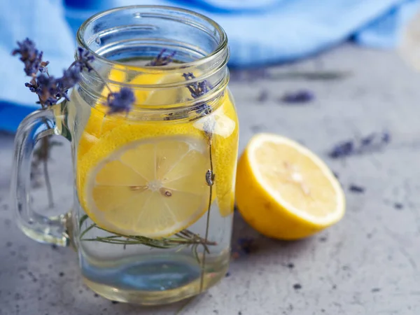 Lavender water with lemon in a jar on a blue background
