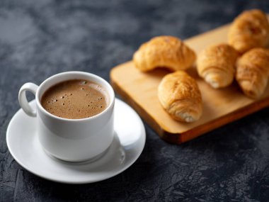 Bir fincan espresso ve küçük bir kahvaltı kruvasanı.