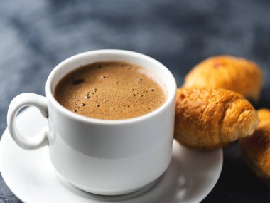 Bir fincan espresso ve küçük bir kahvaltı kruvasanı.