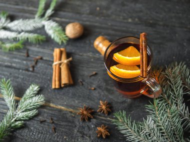 Sıcak kış içeceği koyu ahşap bir masada baharat ve Noel ağacı dallarıyla sulandırılmış şarap.