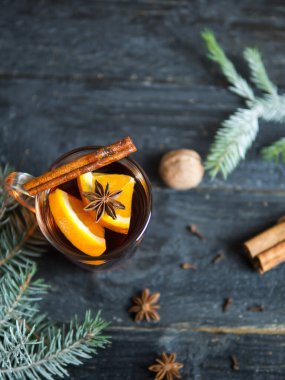 Sıcak kış içeceği koyu ahşap bir masada baharat ve Noel ağacı dallarıyla sulandırılmış şarap.