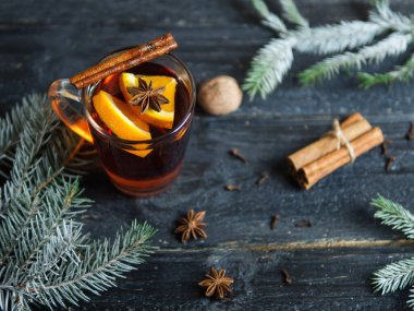 Sıcak kış içeceği koyu ahşap bir masada baharat ve Noel ağacı dallarıyla sulandırılmış şarap.