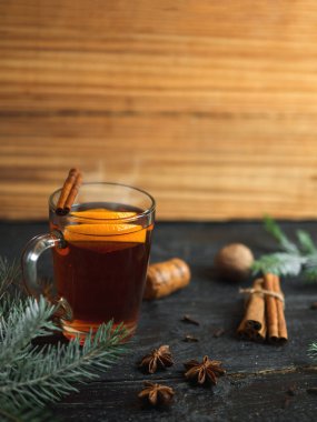 Sıcak kış içeceği koyu ahşap bir masada baharat ve Noel ağacı dallarıyla sulandırılmış şarap.
