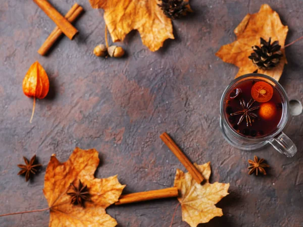 Bir bardak ev yapımı sonbahar şarabı tarçınlı, baharatlı, kumkatlı ve sonbahar kuru yapraklı.