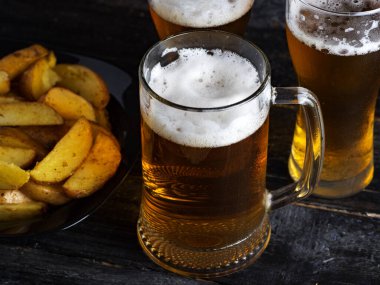 Üç bardak light bira ve koyu bir masada patates.