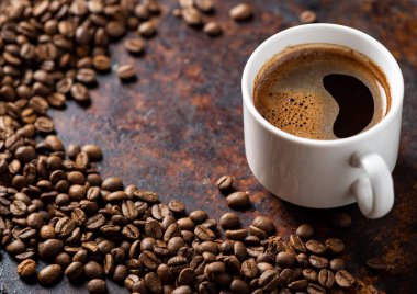 Paslı arka planda bir fincan espresso, yanında da kızarmış kahve çekirdekleri. Boşluğu kopyala