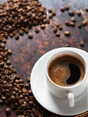 Paslı arka planda bir fincan espresso, yanında da kızarmış kahve çekirdekleri. Boşluğu kopyala