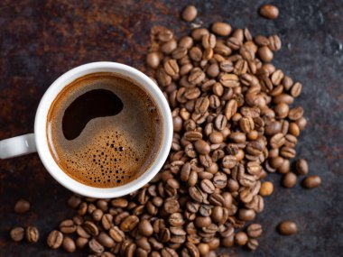 Paslı arka planda bir fincan espresso, yanında da kızarmış kahve çekirdekleri. Boşluğu kopyala