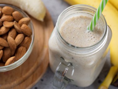 Kavanozdaki ahşap masada taze muz suyu. Yulaf ezmesi ve bademle